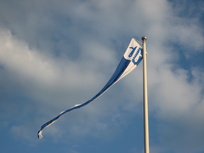Kuva Suodenniemen isännänviiristä liehumassa lipputangossa pilvipoutaisessa säässä.